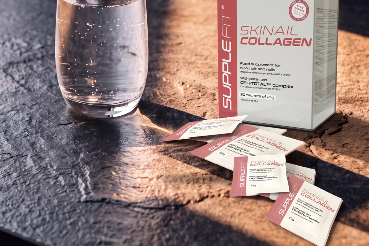 A box of collagen sachets and a glass of water on a dark slate counter in a band of warm morning light