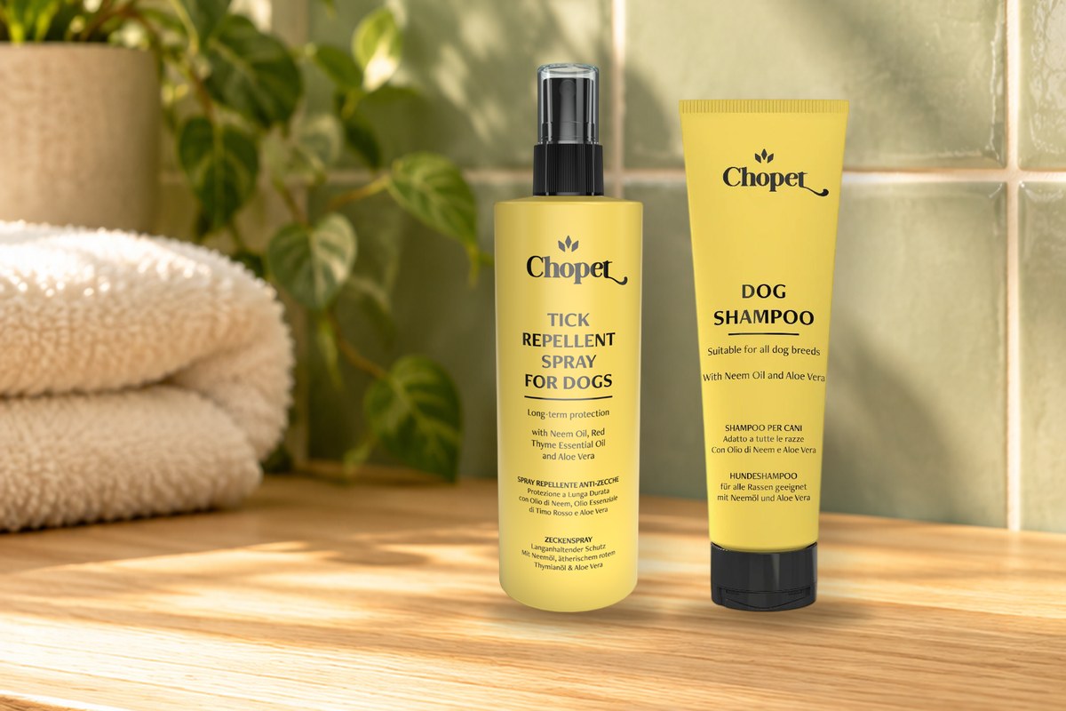 A yellow Chopet tick repellent spray and a tube of dog shampoo on a wooden shelf against sage-green tiles
